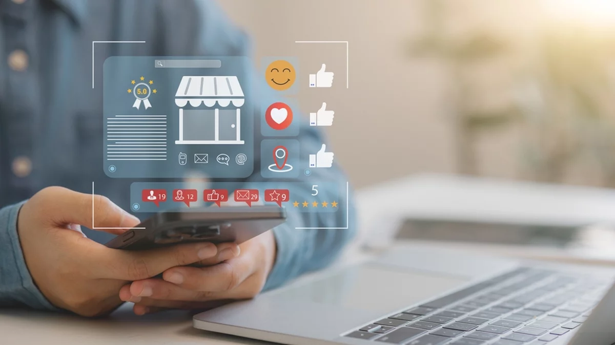 Concept image of small business marketing. Icons of social media likes, et al superimposed over a hand holding a phone.