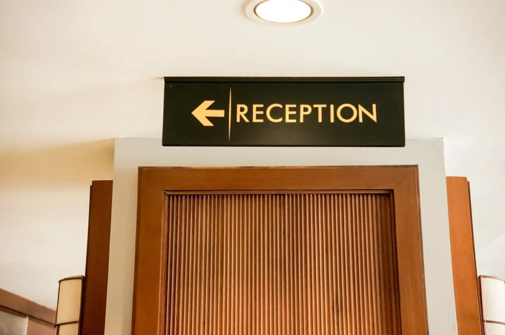 A simple wayfinding sign with the word “RECEPTION” and a left-pointing arrow.