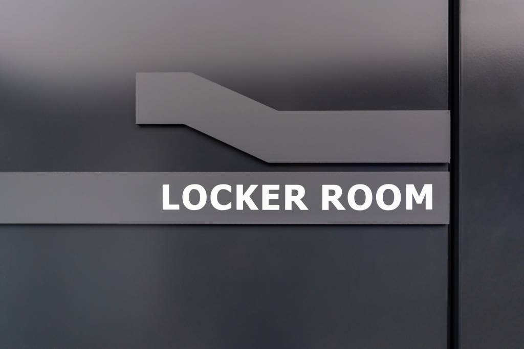 Modern locker room sign on a dark door in a sports or fitness facility.