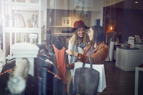 Two women happily shopping in a clothing boutique shop.