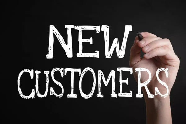 A hand writing the words 'NEW CUSTOMERS' on the screen.