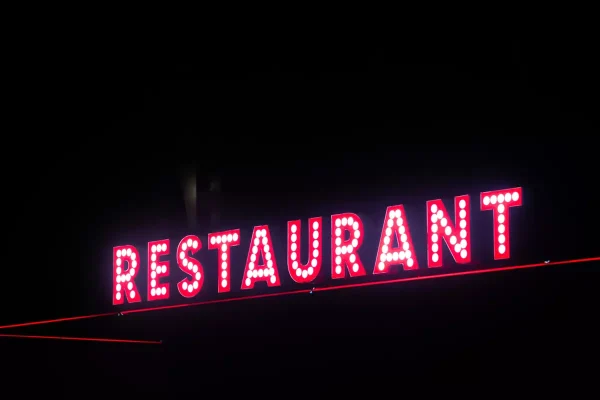 A sign that reads 'RESTAURANT' in neon white on red block letters.