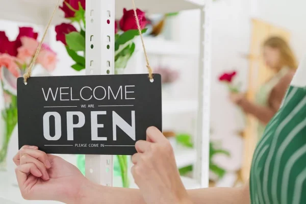 A sign reading 'Come in We’re OPEN' in a flower shop window.