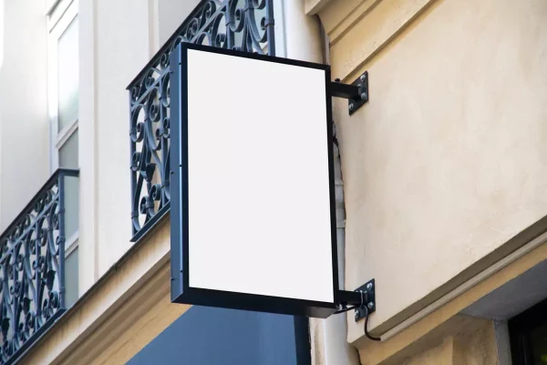 A blank mockup of a rectangular vertical storefront sign on a city street.