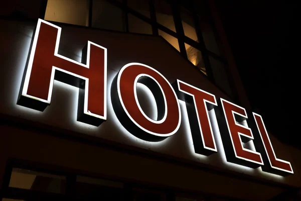 A glowing neon outdoor sign that reads 'HOTEL' in red block letters.